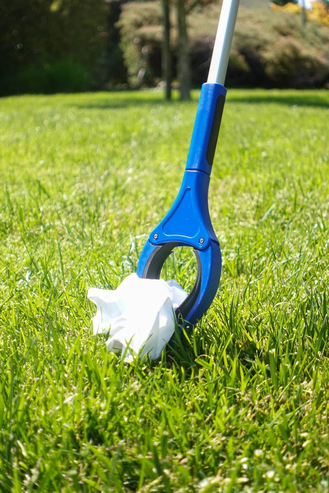 Blue and white grip and grab tool in grass