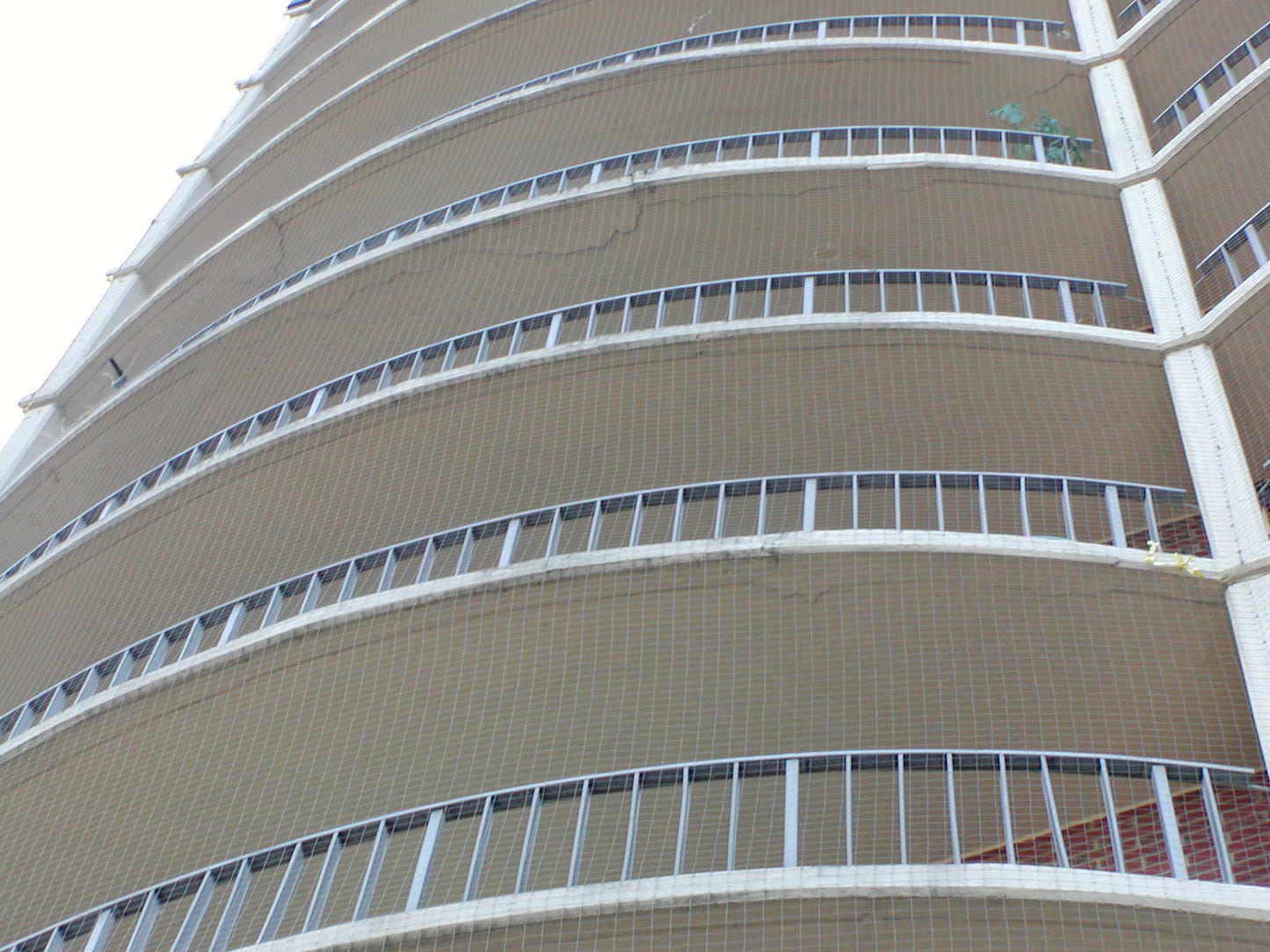 bird barrier net on a tall building with multiple balconies and railings 